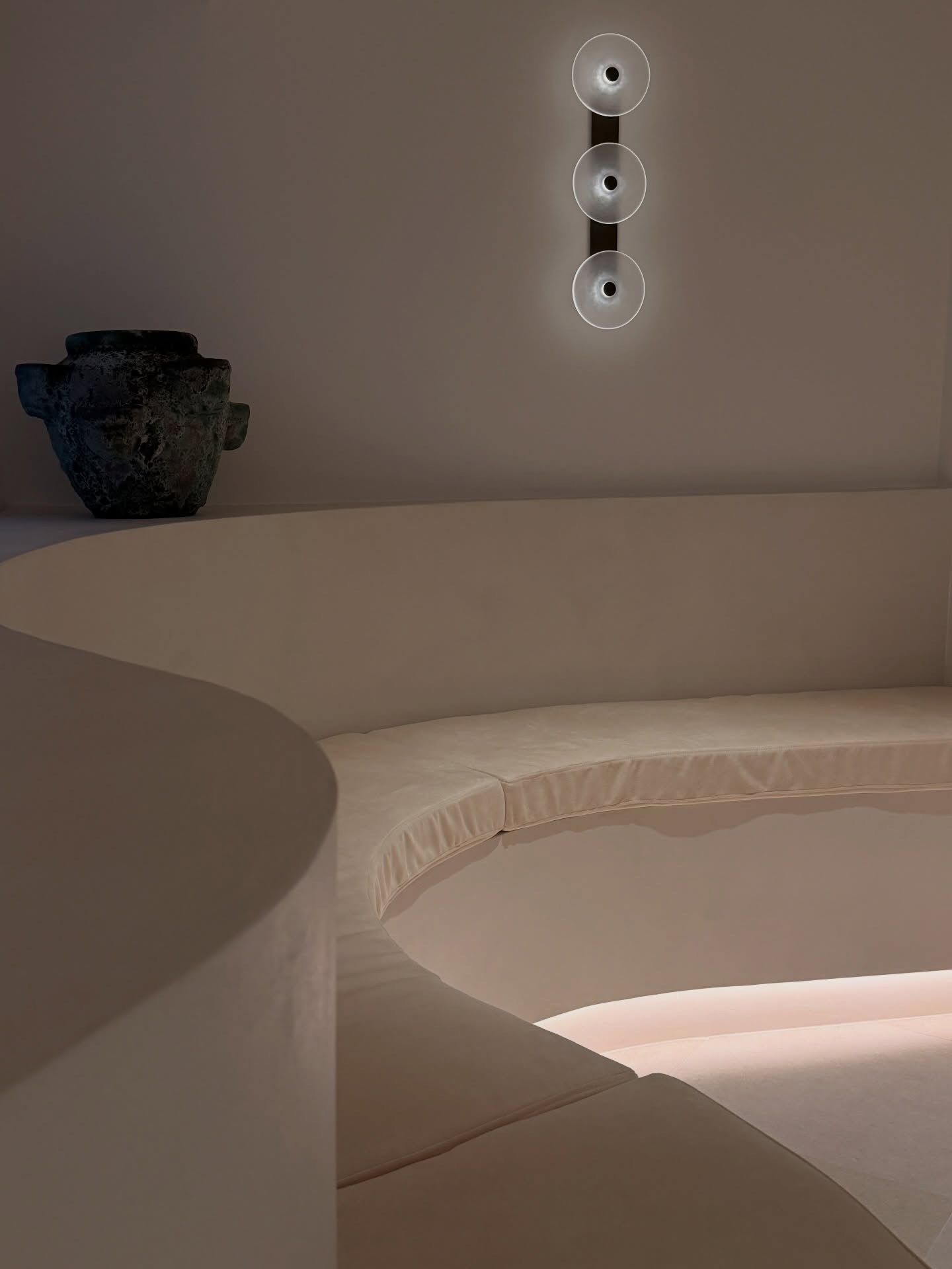 Curved neutral-toned waiting lounge with soft wall lighting at a Bundall cosmetic clinic