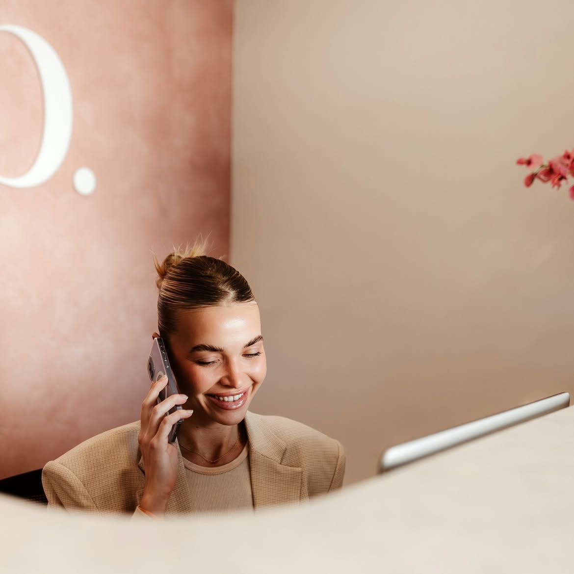 Receptionist taking a booking call at a cosmetic clinic front desk