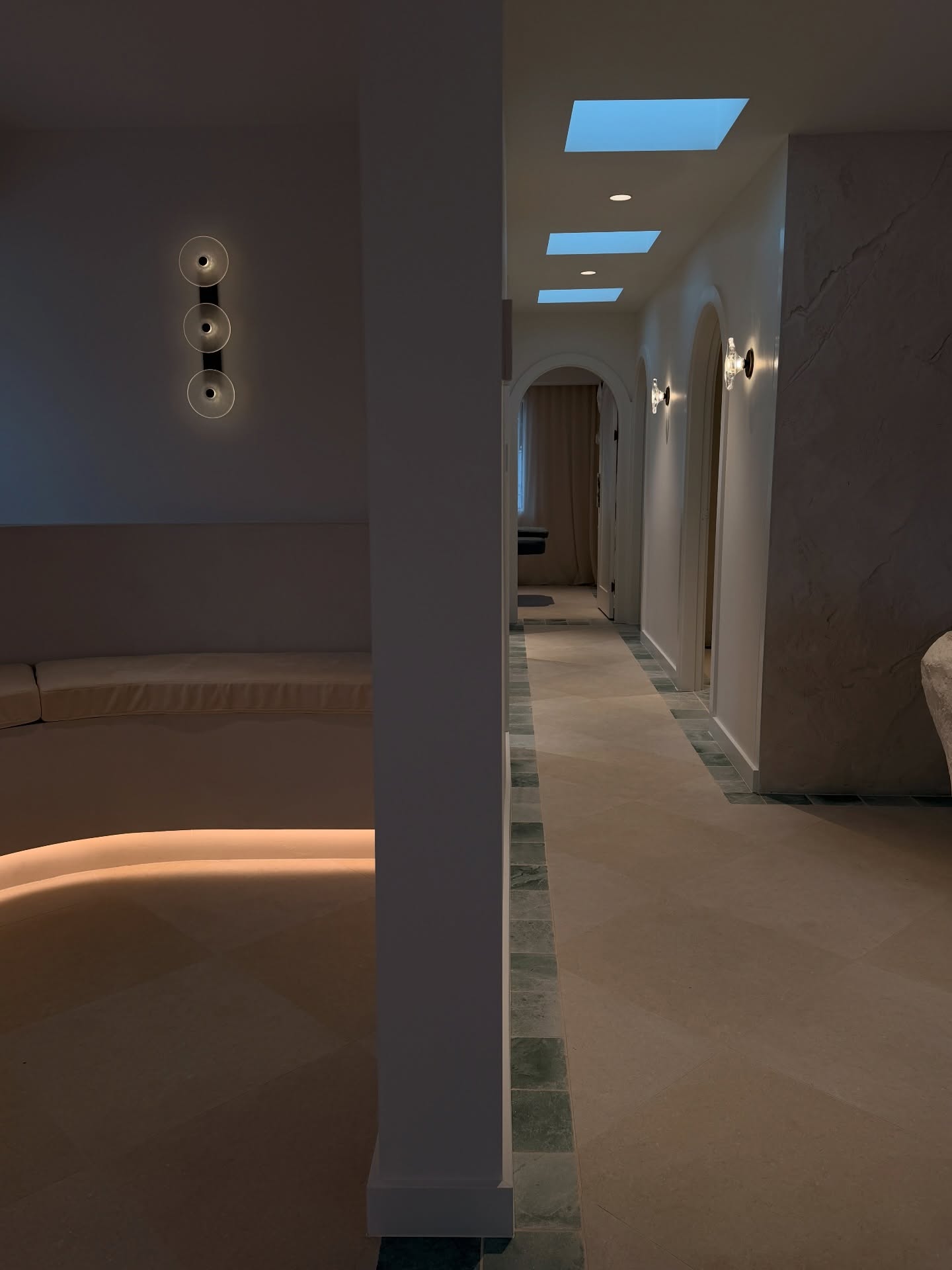 Softly lit corridor with skylights leading to clinic treatment rooms
